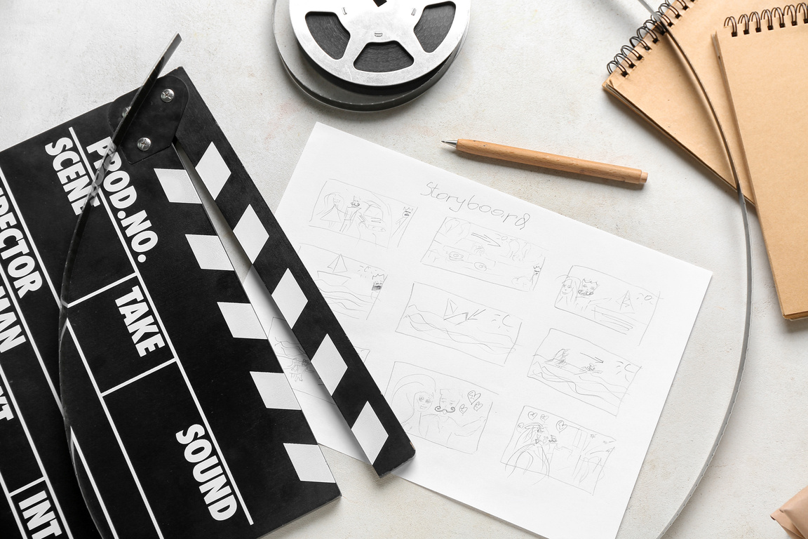 Movie Clapper with Storyboard, Notebooks and Film Reel on Light Background